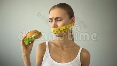 厌食症的女孩用胶带绑住嘴巴，与吃汉堡的诱惑作斗争